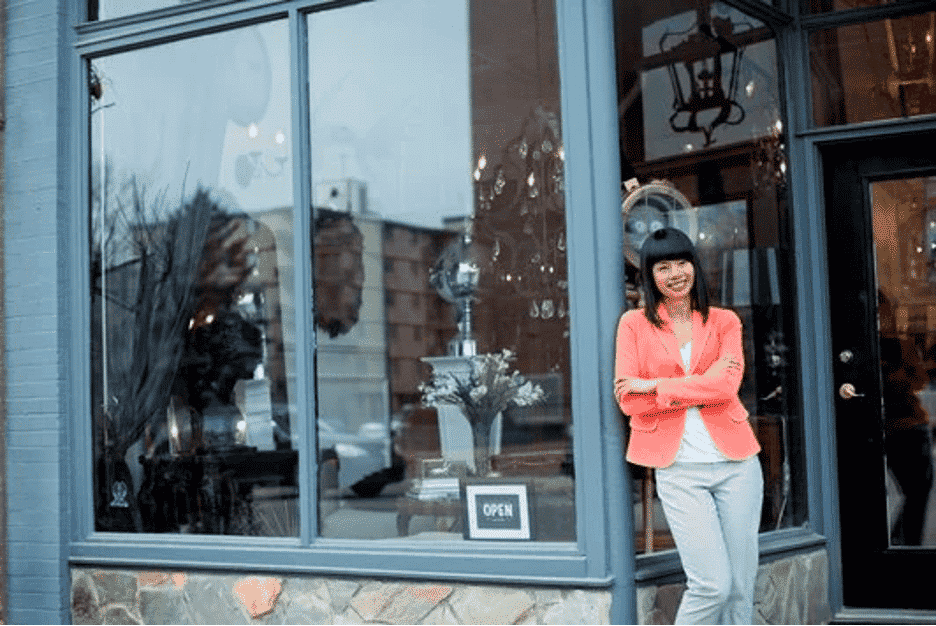 woman leaning against doorframe of high street shop that is utilizing solar window film 